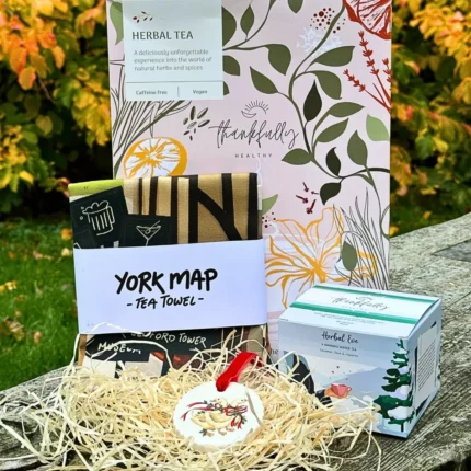 Celebrate the season of giving with our thoughtfully curated Tea Towel, Tea, and Handcrafted Christmas Disc Gift Box. This delightful hamper features one of our winter bestseller herbal tea, complementing it is a beautiful, hand-illustrated York City tea towel, printed on organic cotton—a unique and eco-conscious addition to any kitchen. To complete the festive charm, the set includes a handcrafted Christmas novelty disc featuring a traditional Christmas design, tied with a luxurious velvet ribbon.